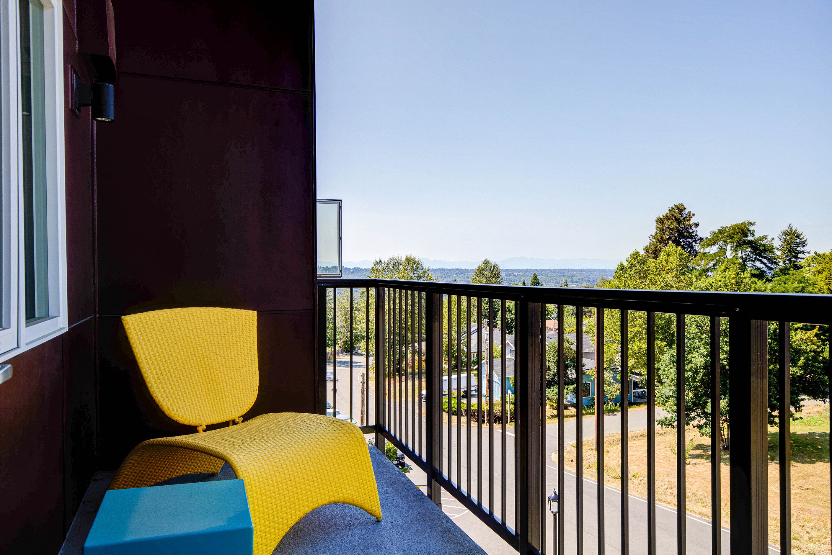 Private Patio Overlooking Parking Lot with Yellow Chair, Gate and Trees